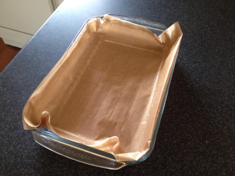rectangular metal baking sheet and roll of brown parchment paper